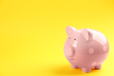 Pink piggy bank on yellow background. Space for text
