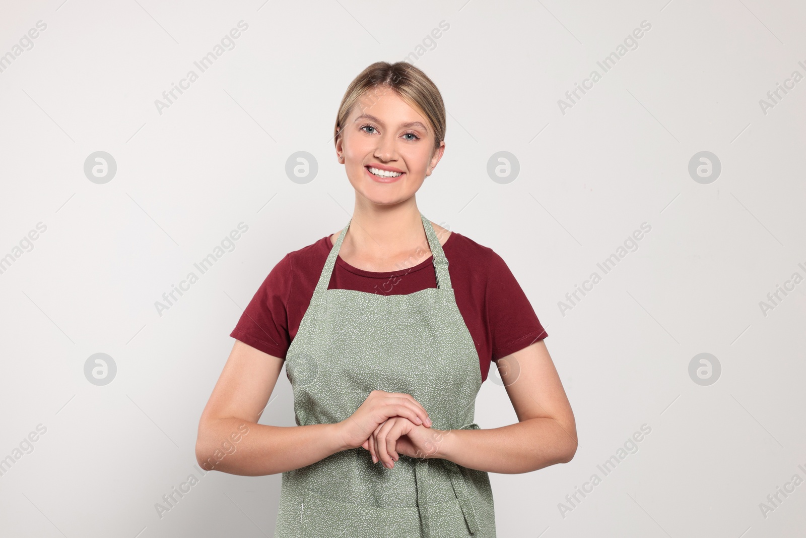 Photo of Beautiful young woman in clean apron on light grey background