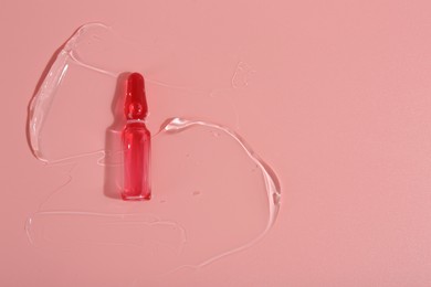 Photo of Skincare ampoule on pink surface with gel, top view. Space for text