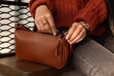Photo of Fashionable woman with stylish bag on bench outdoors, closeup