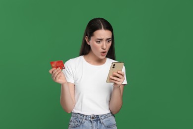 Photo of Shocked woman with credit card and smartphone on green background. Debt problem