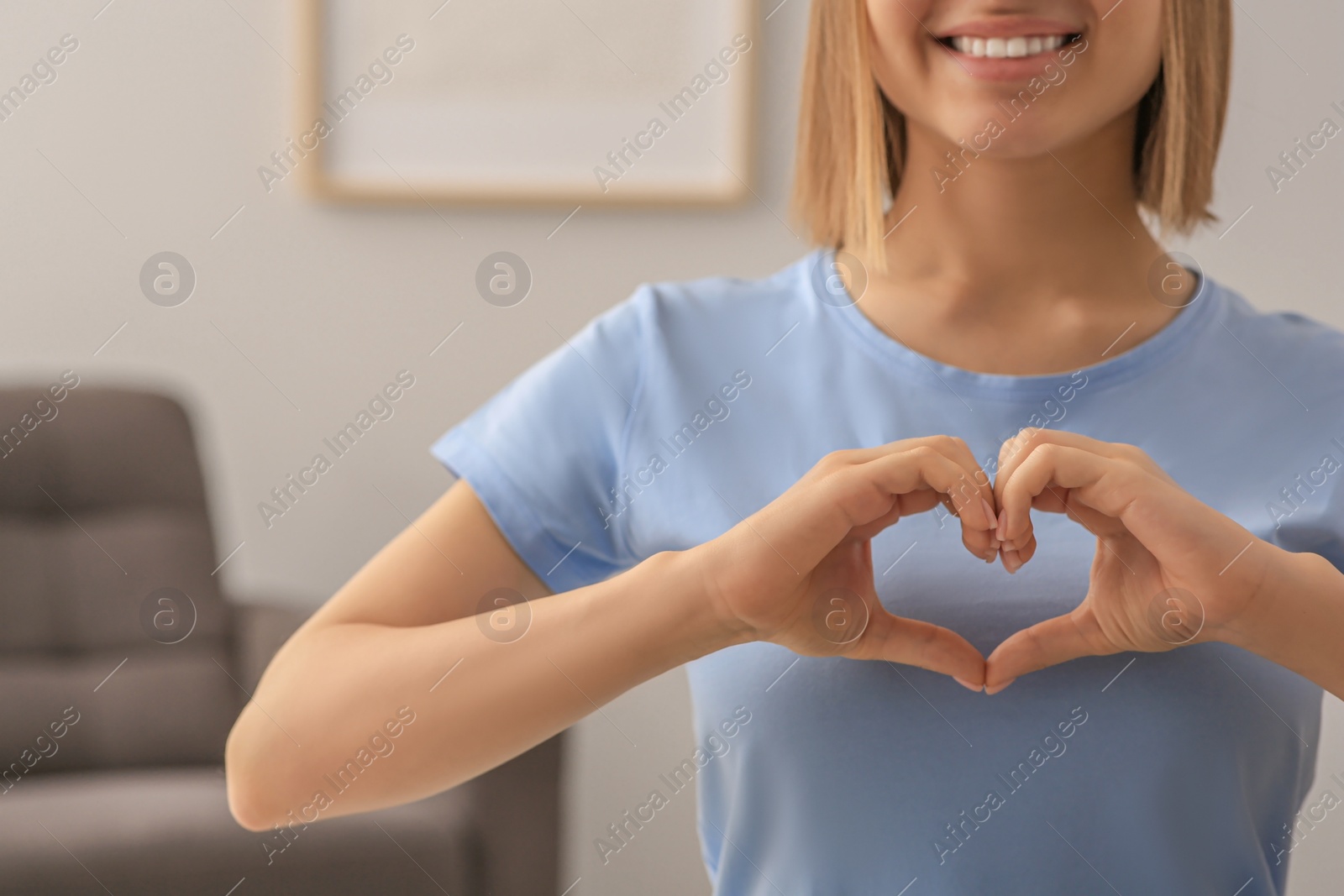 Photo of Young woman making heart with hands indoors, closeup. Volunteer concept