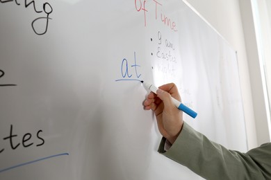 Photo of English teacher giving grammar lesson near whiteboard, closeup