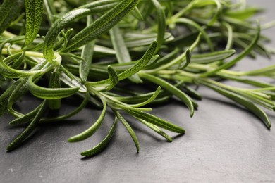 Photo of Aromatic green rosemary sprigs on gray table, closeup