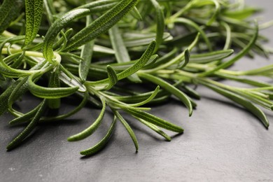 Aromatic green rosemary sprigs on gray table, closeup