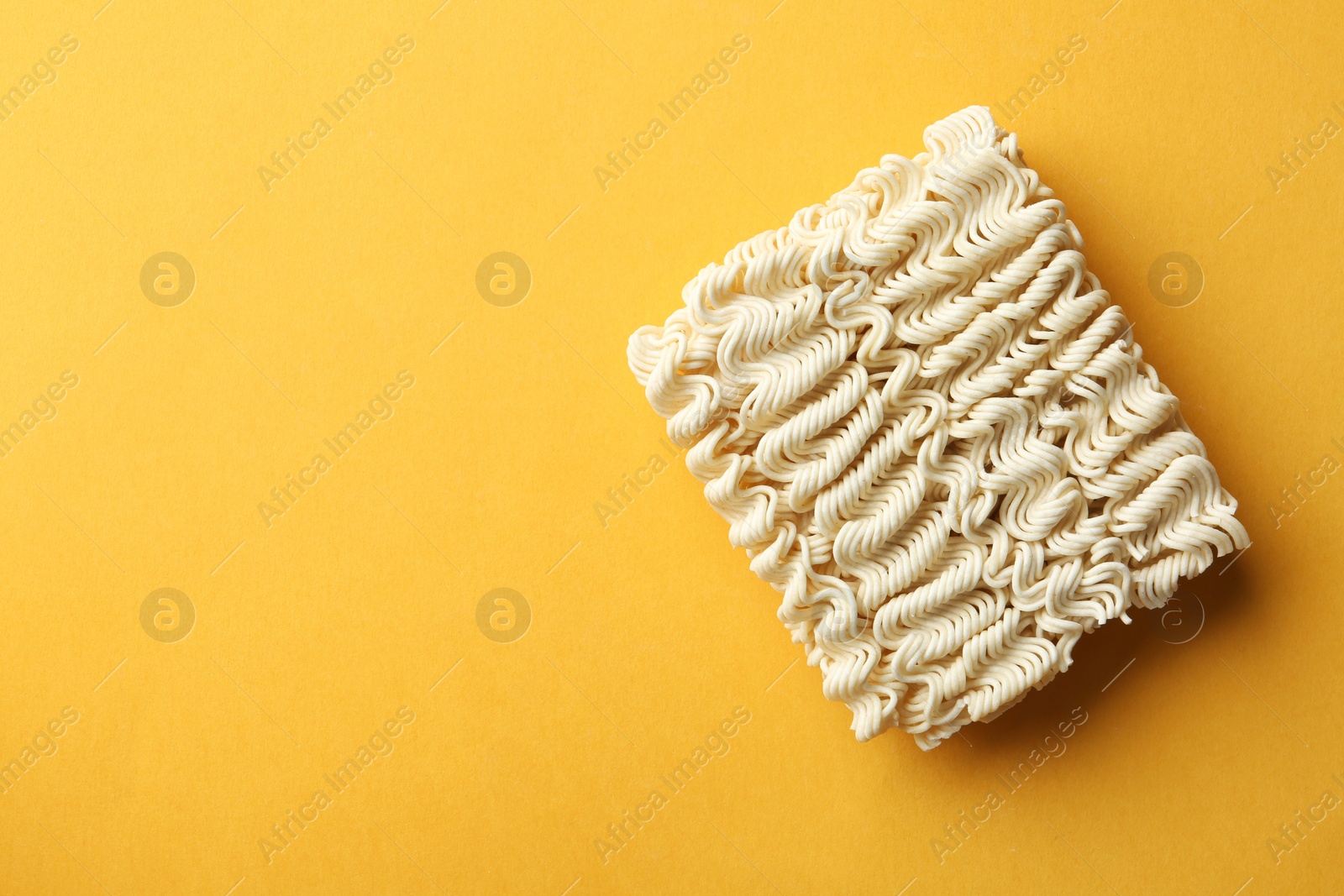 Photo of Block of quick cooking noodles on color background, top view. Space for text