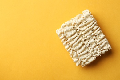 Photo of Block of quick cooking noodles on color background, top view. Space for text