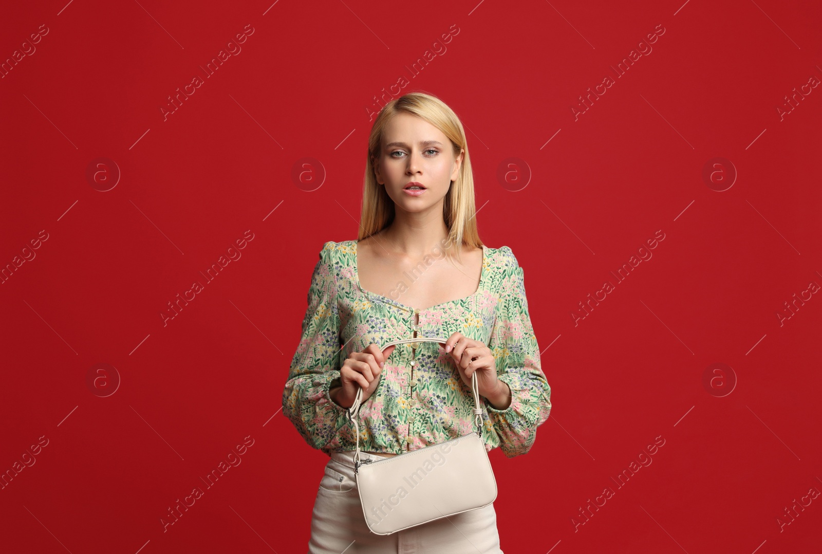 Photo of Beautiful stylish woman with trendy baguette bag on red background