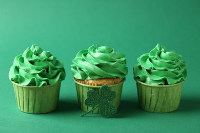 St. Patrick's day party. Tasty cupcakes on green background