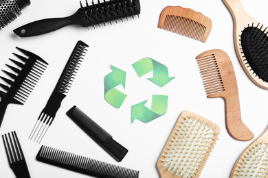 Recycling symbol and different hairbrushes on white background, top view