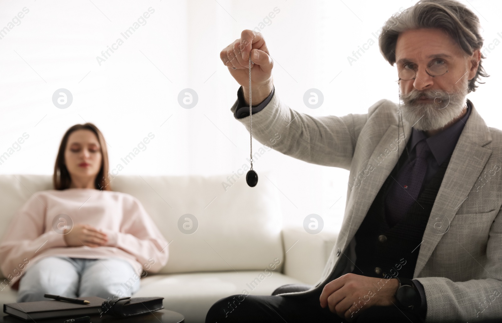 Photo of Psychotherapist using pendulum during hypnotherapy   session in office