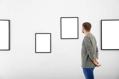 Photo of Young man viewing exposition in modern art gallery