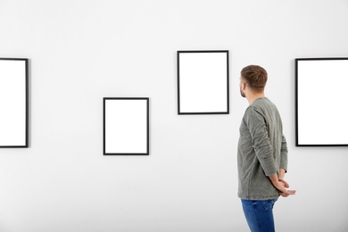 Young man viewing exposition in modern art gallery