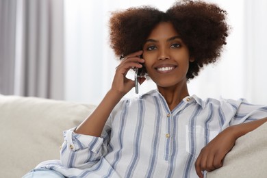 Photo of Smiling African American woman talking on smartphone at home. Space for text