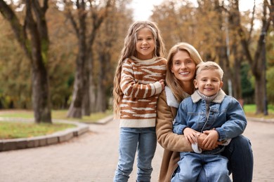 Portrait of happy mother and her children in autumn park, space for text