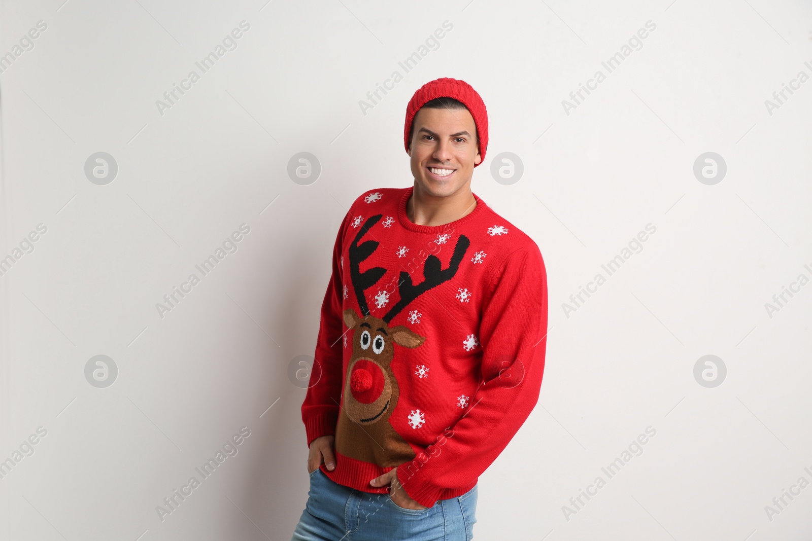 Photo of Handsome man in Christmas sweater and hat on white background