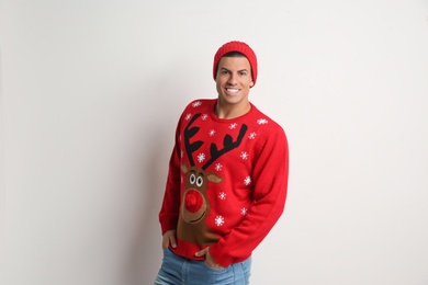Photo of Handsome man in Christmas sweater and hat on white background