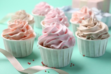 Photo of Delicious birthday cupcakes, ribbon and sprinkles on turquoise background, closeup