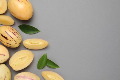 Whole and cut pepino melons on grey background, flat lay. Space for text