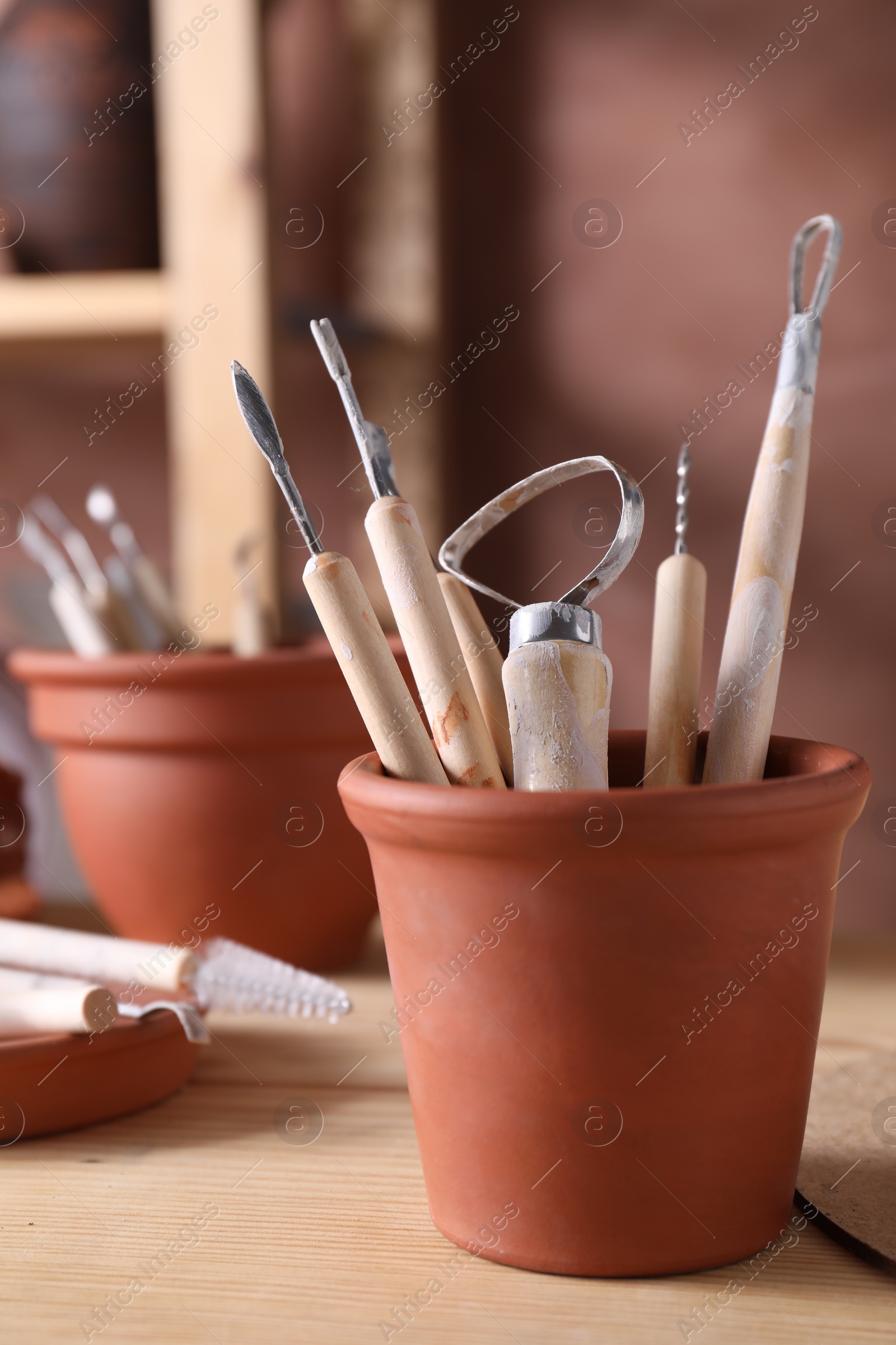 Photo of Set of different clay crafting tools on wooden table in workshop