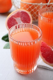 Photo of Tasty freshly made grapefruit juice on light grey marble table