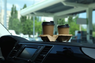 Paper coffee cups on car dashboard at gas station