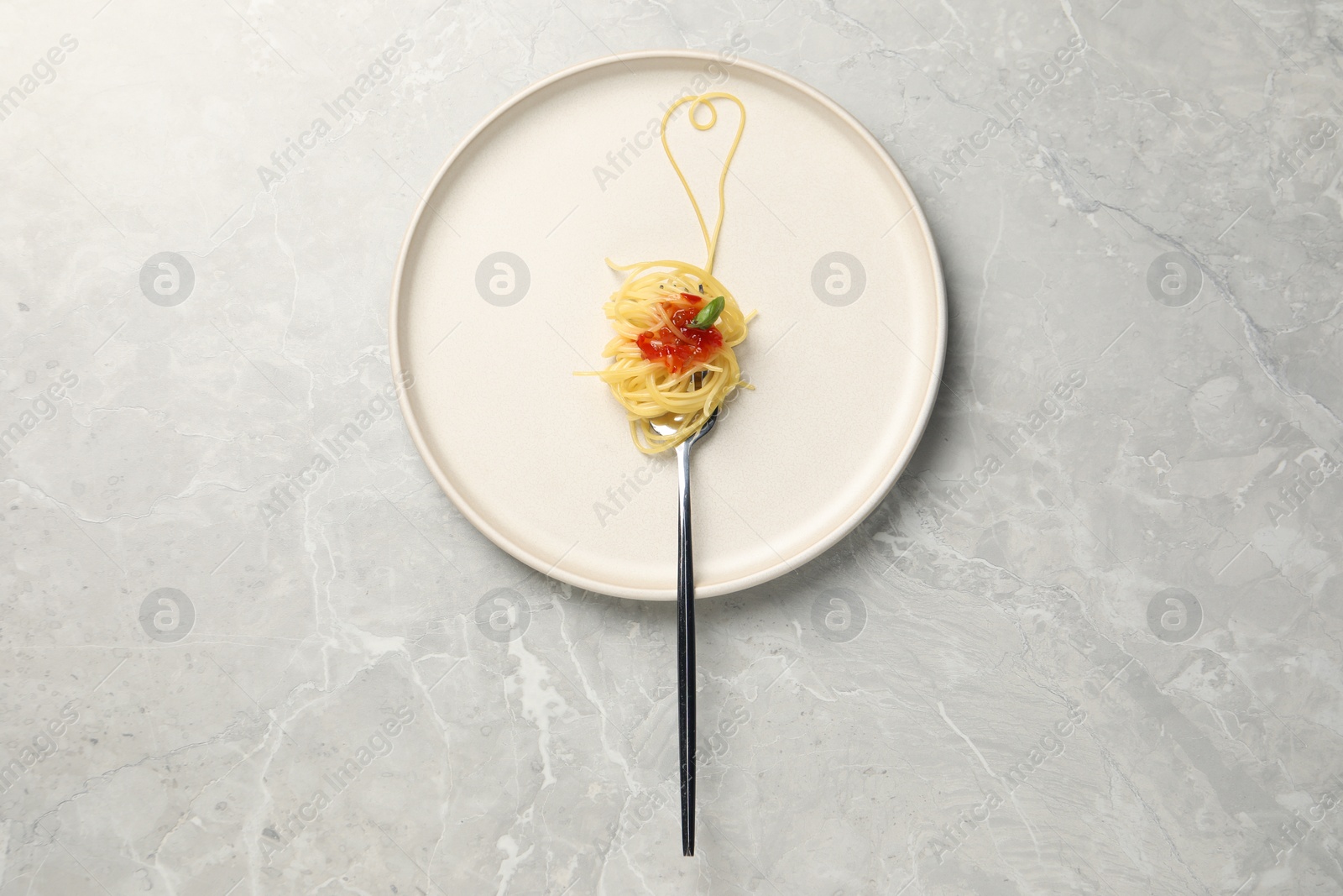 Photo of Heart made with spaghetti and fork on grey table, top view