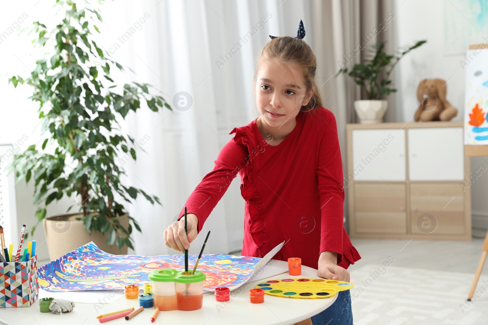 Photo of Little child painting picture at table indoors