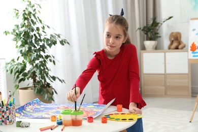 Photo of Little child painting picture at table indoors