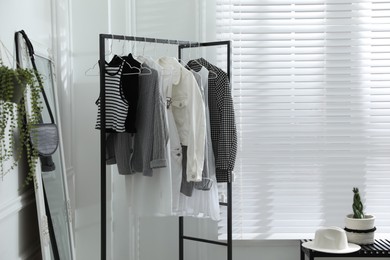 Rack with stylish women's clothes and large mirror in dressing room. Interior design