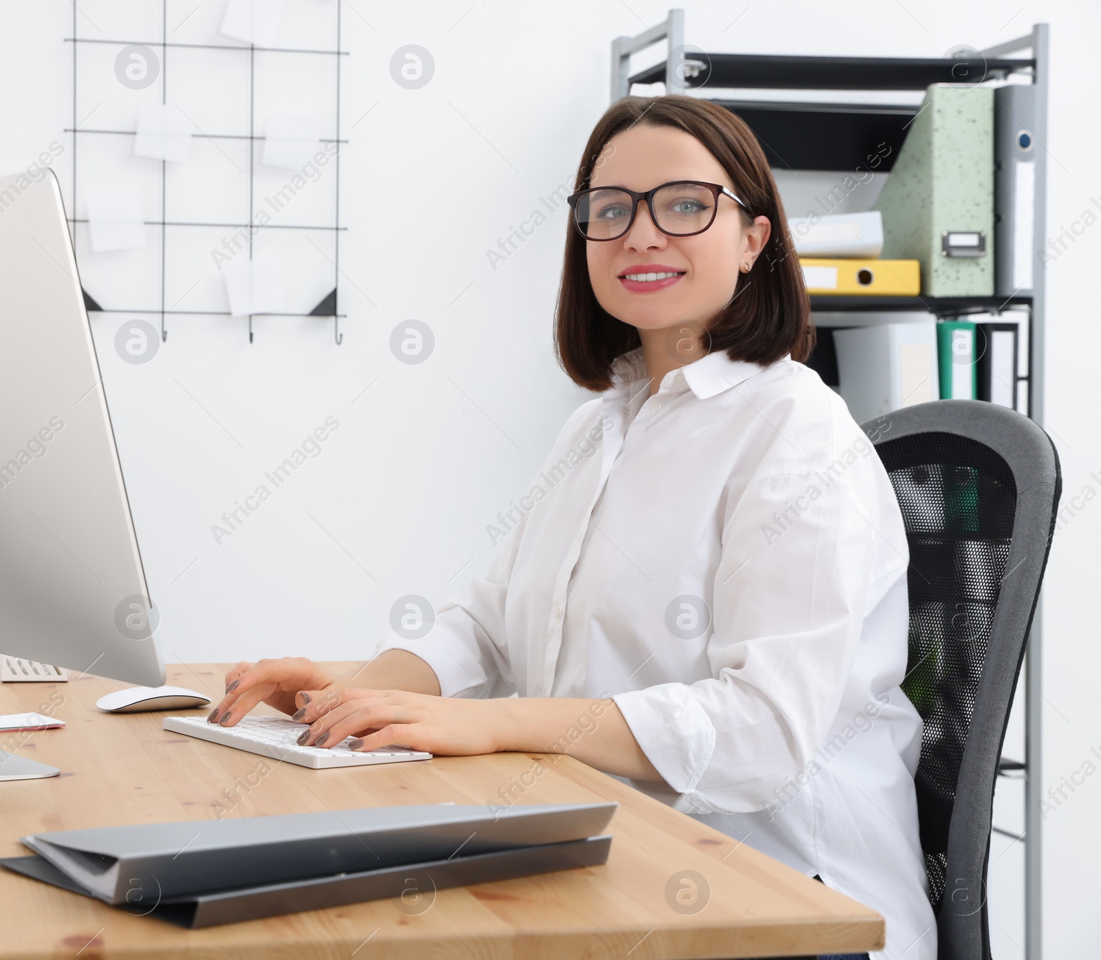 Photo of Happy young intern working with computer at table in modern office