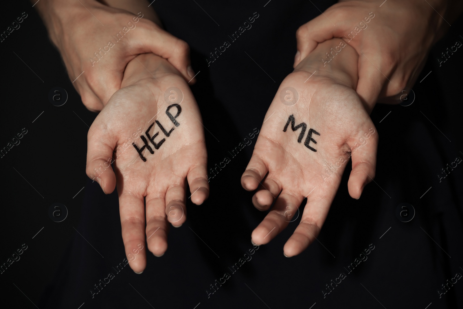 Photo of Man holding woman's hands with words HELP ME on dark background, closeup. Stop sexual assault