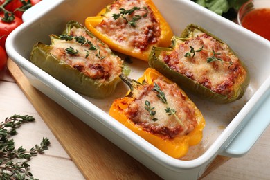 Photo of Tasty stuffed peppers in dish on wooden table, closeup