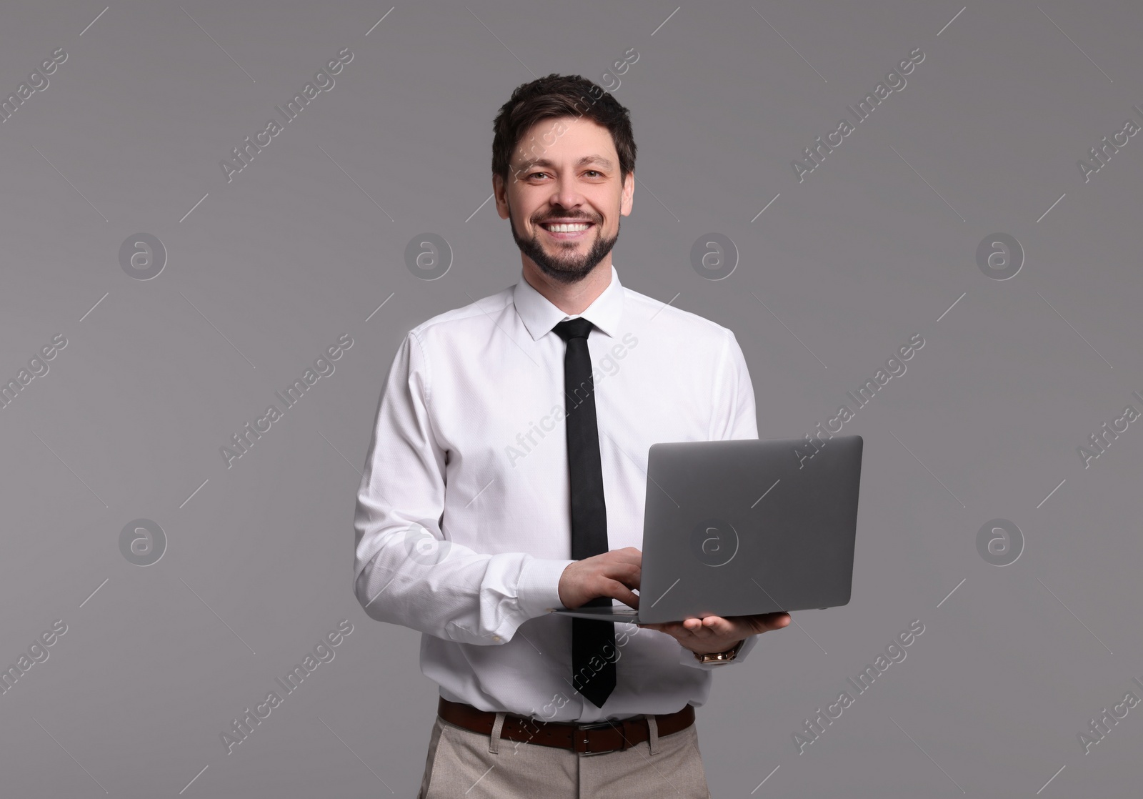 Photo of Happy man with laptop on grey background