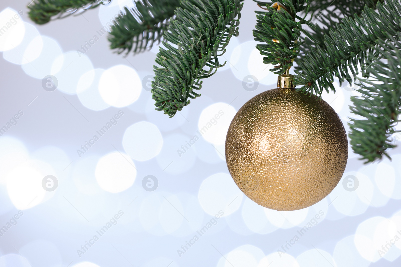 Photo of Beautiful holiday bauble hanging on Christmas tree against blurred lights, closeup. Space for text