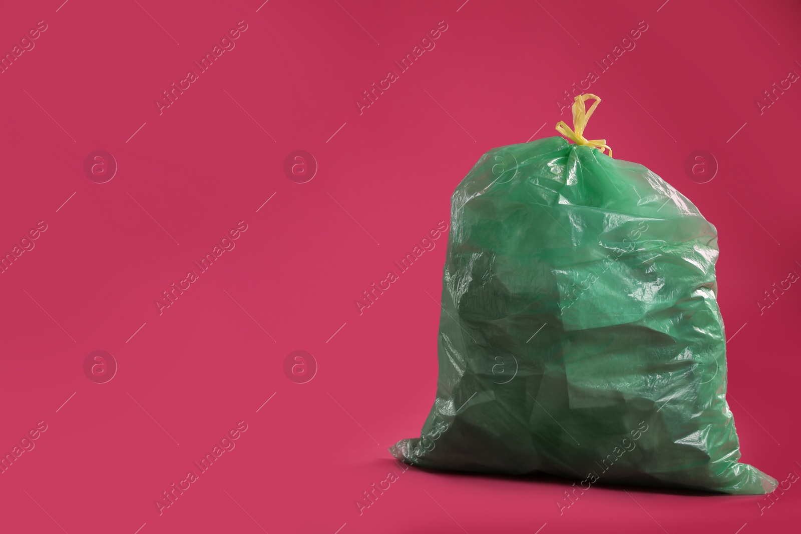 Photo of Trash bag full of garbage on pink background. Space for text