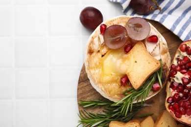 Flat lay composition with tasty baked camembert on white tiled table. Space for text