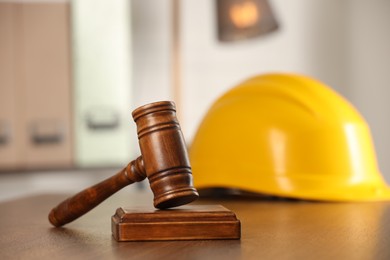Photo of Law concept. Gavel and yellow hard hat on wooden table