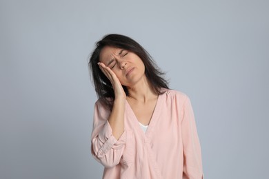 Photo of Mature woman suffering from headache on light grey background