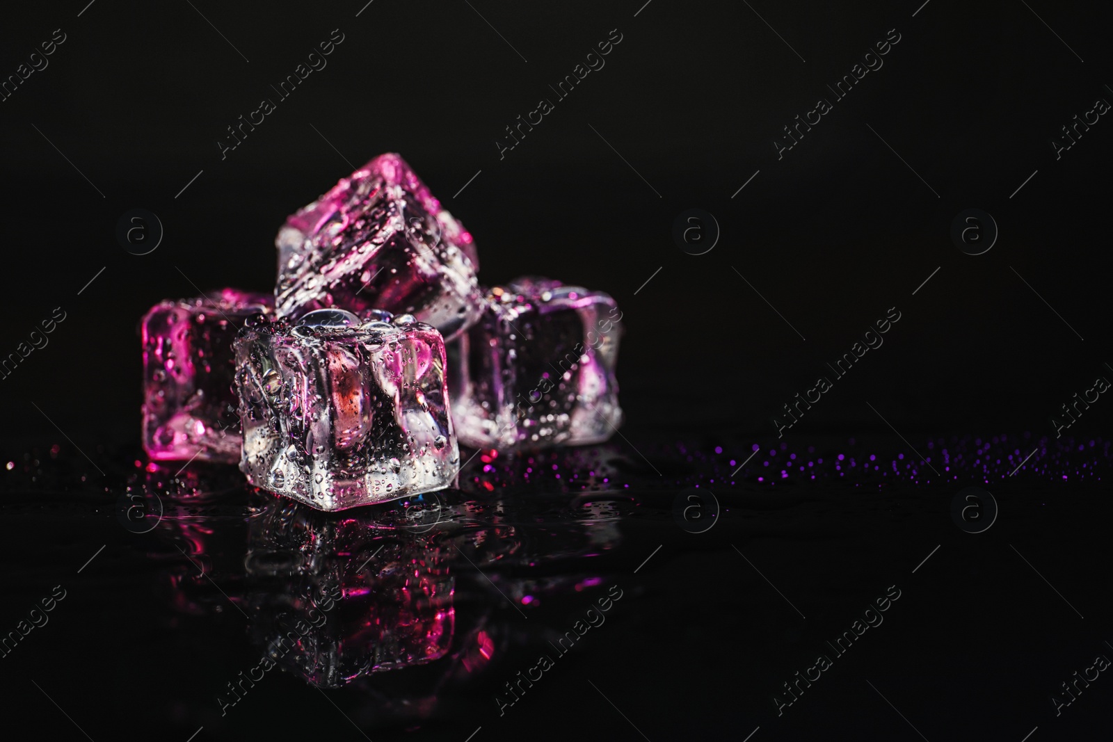 Photo of Pile of crystal clear ice cubes on black background. Space for text