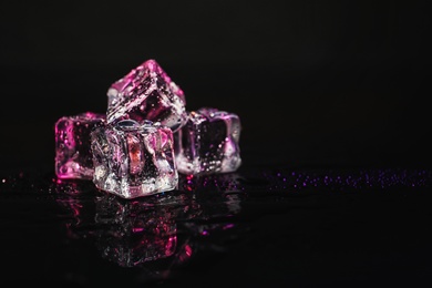 Photo of Pile of crystal clear ice cubes on black background. Space for text