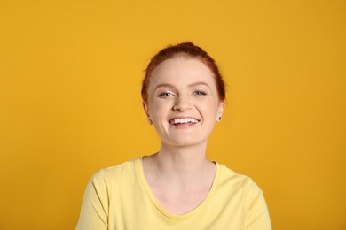 Photo of Candid portrait of happy red haired woman with charming smile on yellow background