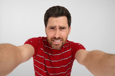 Photo of Emotional man taking selfie on white background