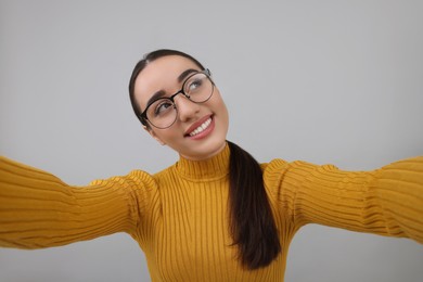 Photo of Smiling young woman taking selfie on grey background