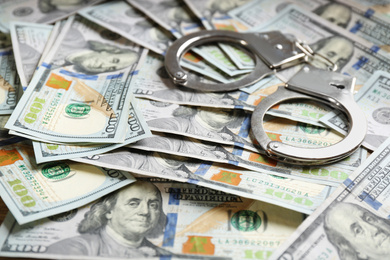 Photo of Handcuffs on dollar bills pile. Bribe concept