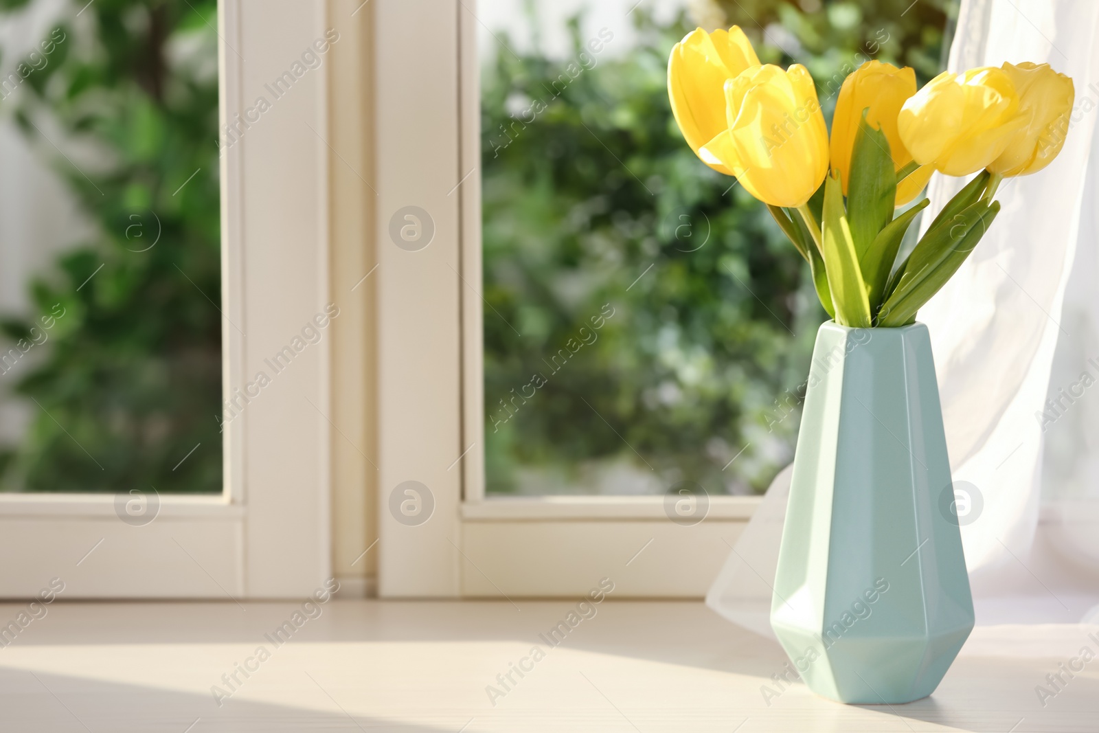 Photo of Beautiful fresh yellow tulips on window sill indoors. Spring flowers