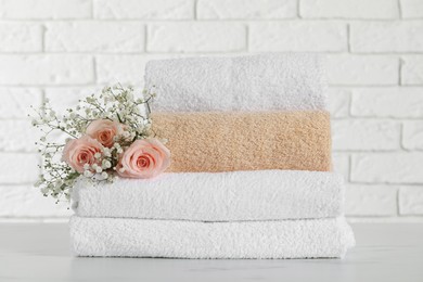 Photo of Stack of folded colorful towels with roses on white table