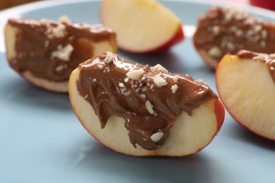 Photo of Slices of fresh apple with nut butter and chopped nuts on plate, closeup