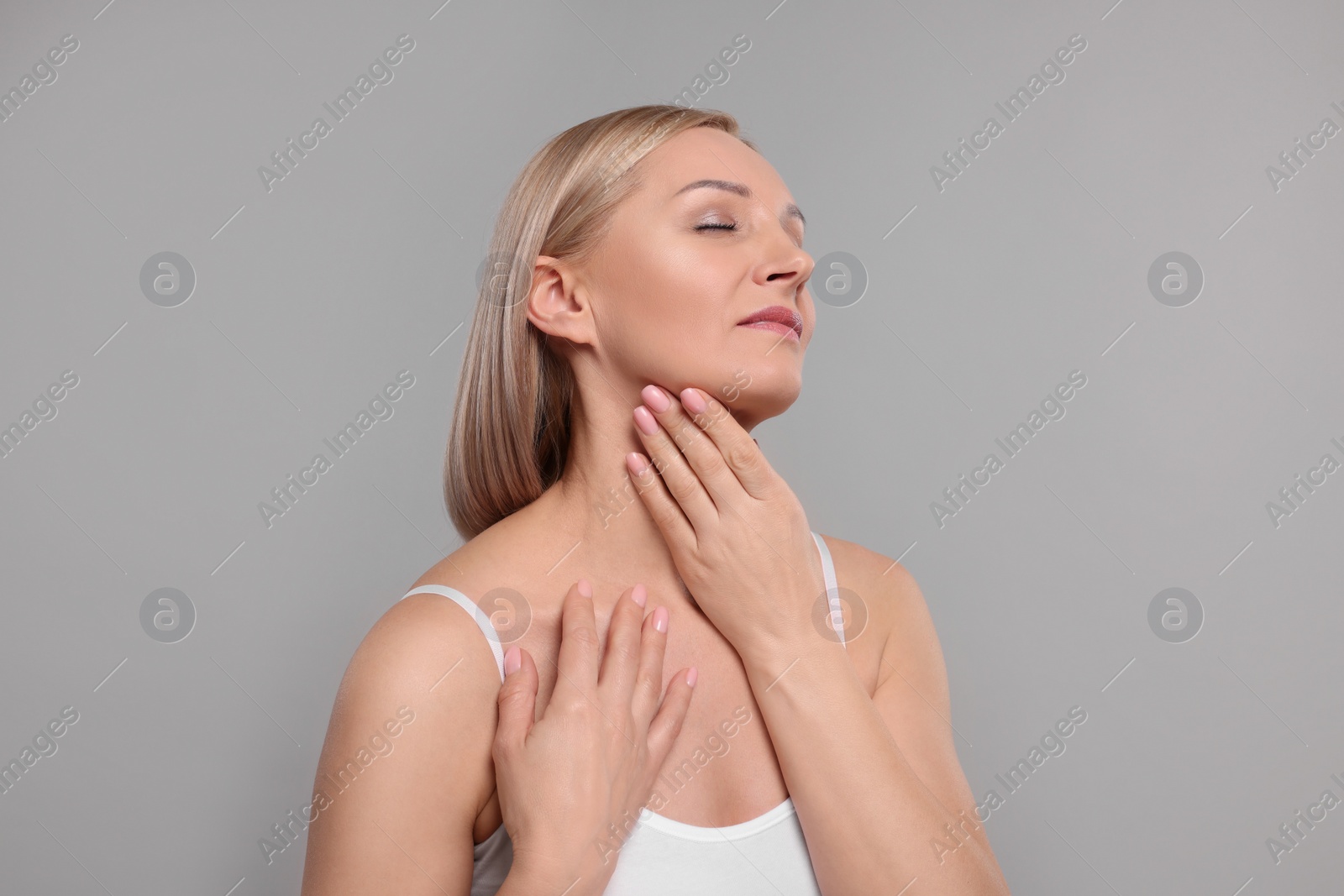 Photo of Beautiful woman touching her neck on grey background