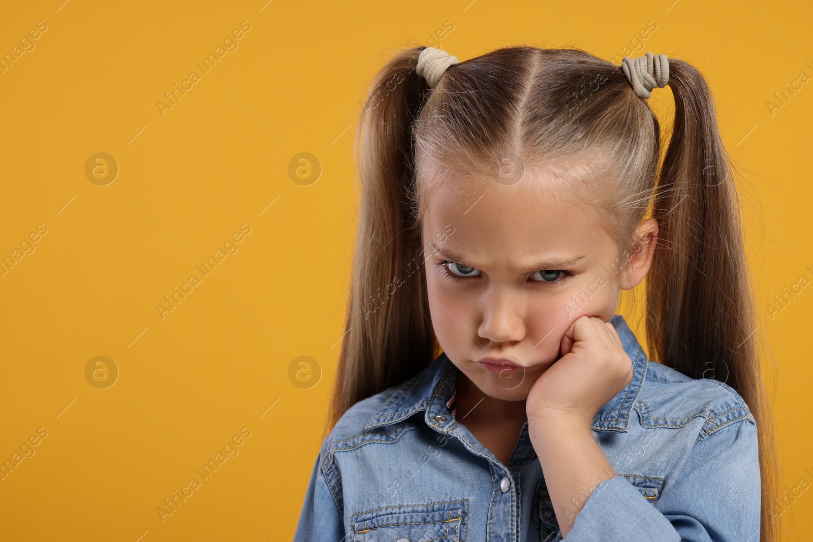 Photo of Resentful girl on orange background. Space for text